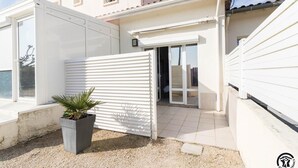 Un edificio residenziale con cancello automatico, porta scorrevole e una pianta in vaso.
