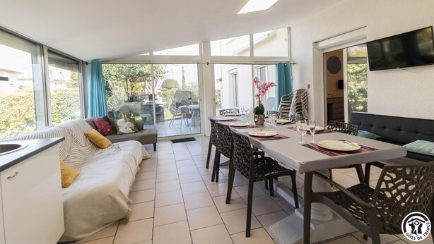 Un interno moderno con zona pranzo, divano, cucina e ampie finestre.