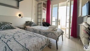 Una camera d'albergo con due letti, una televisione, una scrivania e vista sull'esterno.