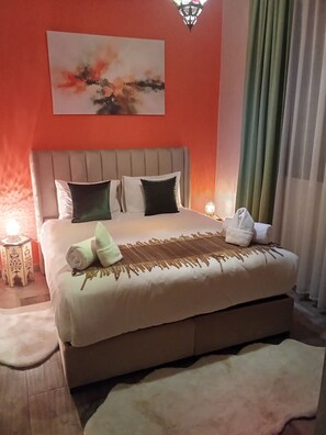 Ein Hotelzimmer mit Bett, Kissen, Decke, Handtuch, Nachttisch, Lampe und einem Bild an der Wand.