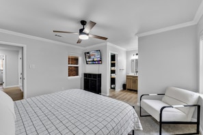 A bedroom with a bed, a ceiling fan, a TV, and a white chair. - Bedford Bungalow Prime DFW Location Near Everything (Bedford)