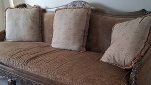 En soffa i vintage-stil med utsmyckade ben och kuddar med blommönster.