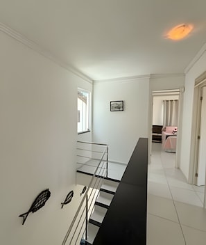 Uma escadaria com corrimão, janela e um quadro pendurado na parede.