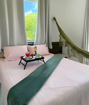 A bed with a green bedspread, two pink pillows, a tray with a glass of red drink, and a green cup. - Pérola do Atlântico - Ponta de Campina (Cabedelo)