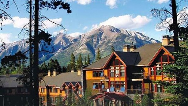 Un chalet avec une vue imprenable sur les montagnes, doté d’une entrée imposante, de plusieurs cheminées et d’un jardin bien entretenu.