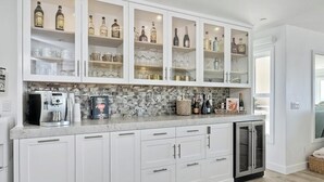 A kitchen with white cabinets, a built-in wine cooler, and a coffee machine.