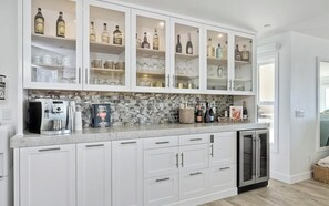 A kitchen with white cabinets, a built-in wine cooler, and a coffee machine.