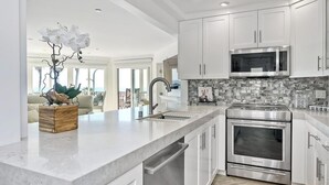 A modern kitchen with white cabinets, a stainless steel oven, and a marble countertop.