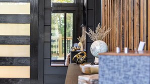 A room with a wooden wall, a window with a view, and a table with decorative items. - Romantic Cabin - Hot Tub, Fire Pit Near Gatlinburg (Sevierville)
