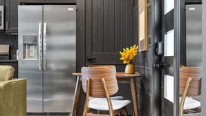 A modern kitchen with a stainless steel refrigerator, a water dispenser, and a dining area with wooden chairs and a small table. - Romantic Cabin - Hot Tub, Fire Pit Near Gatlinburg (Sevierville)