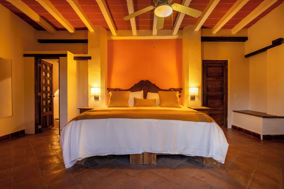 A bedroom with a large bed, wooden headboard, two bedside tables, and a ceiling fan.