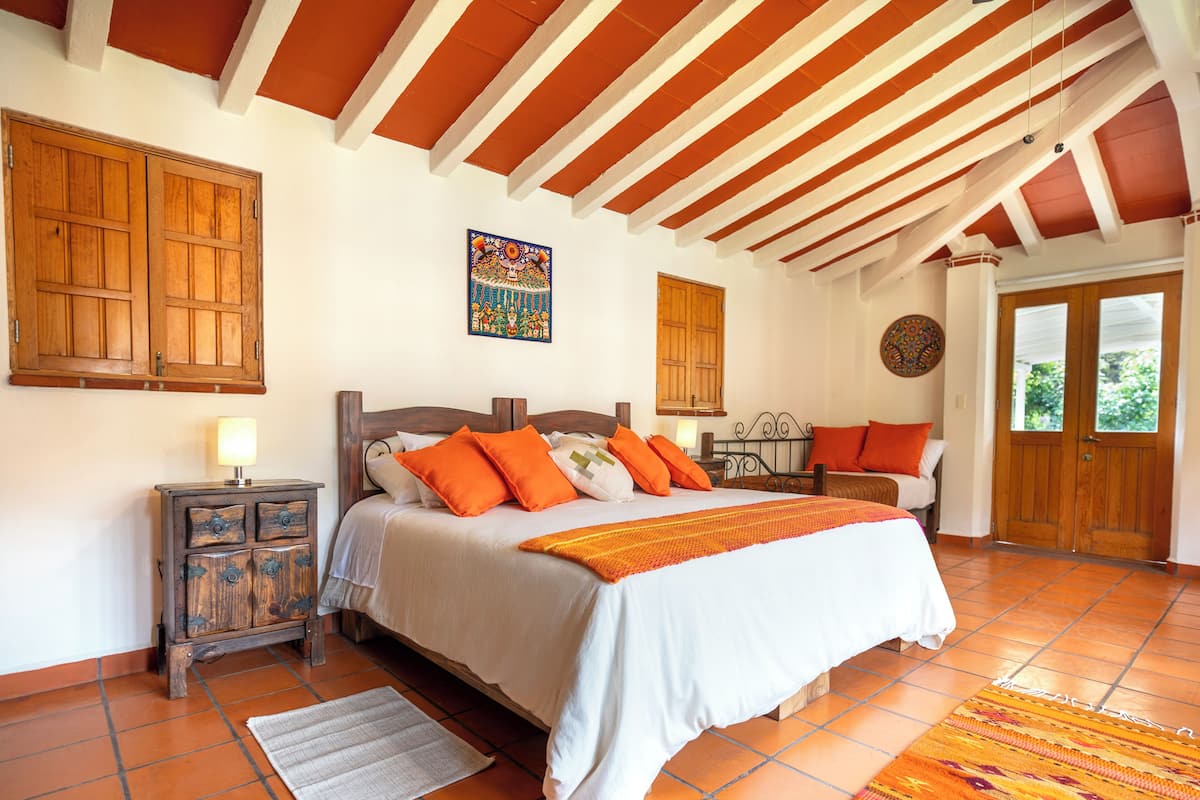 A bedroom with a bed, wooden wardrobe, and a window.