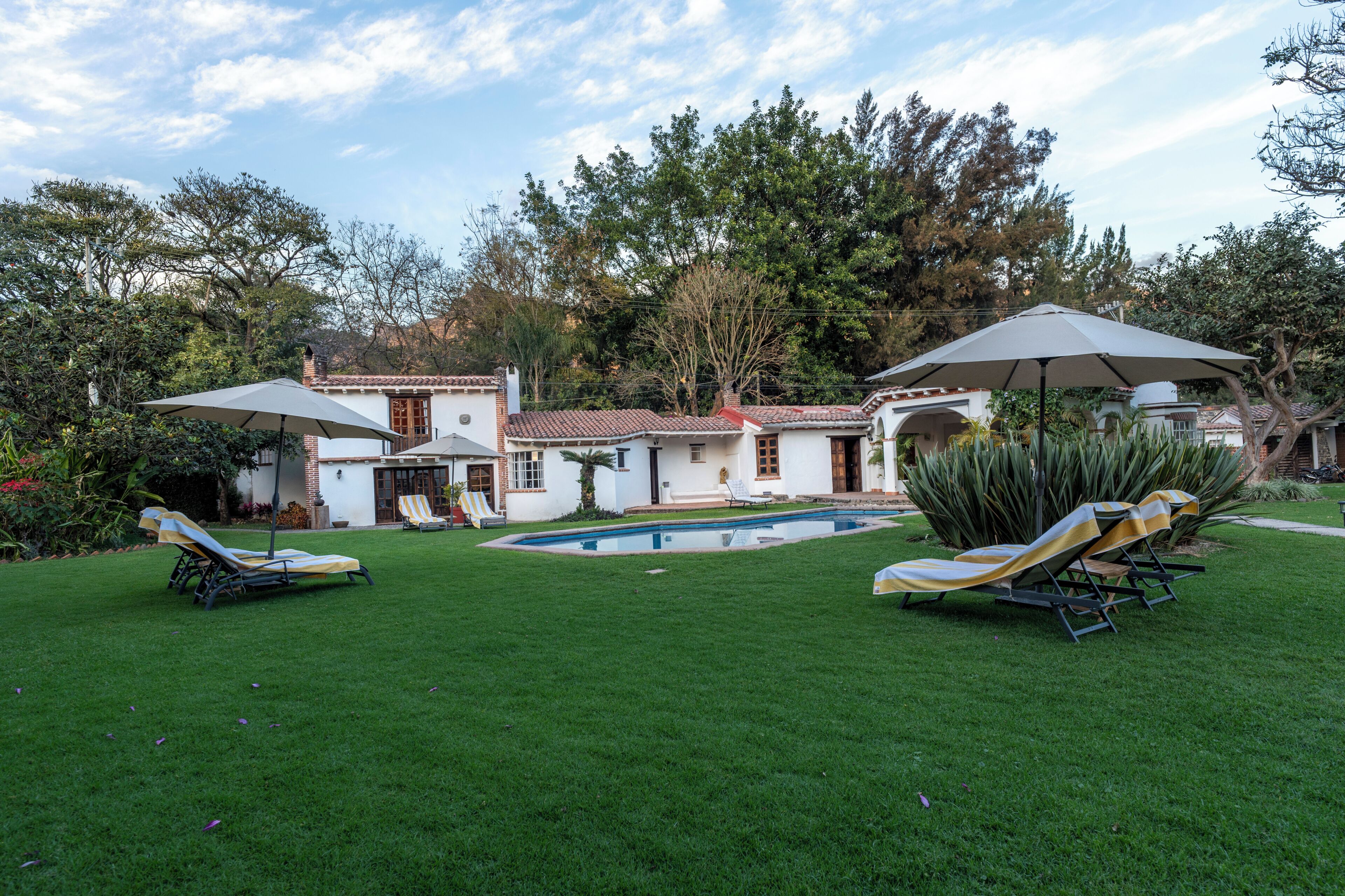 Una piscina al aire libre, sombrillas, sillones reclinables de piscina