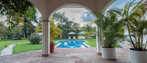 Una piscina al aire libre, sombrillas, sillones reclinables de piscina
