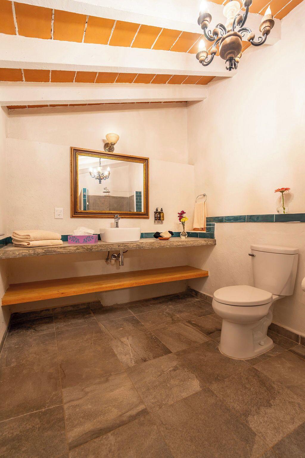 Ein Badezimmer mit einem großen Spiegel, einem Waschbecken, einer Toilette und einem Holzregal.