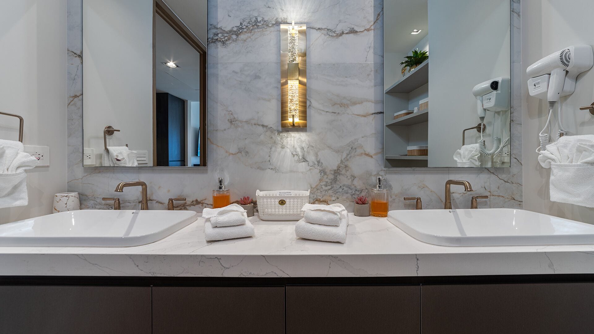 Une salle de bain moderne avec deux lavabos, un luminaire central et un miroir.