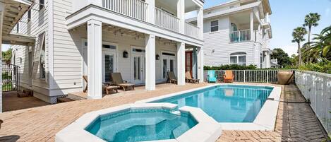 A two-story house with a swimming pool, outdoor seating, and a fenced patio area.