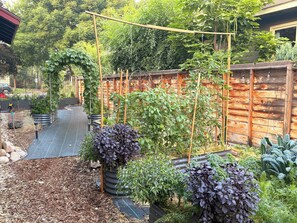 Ein Garten mit erhöhten Beeten, einem Holzzaun und unterschiedlichen Pflanzen.