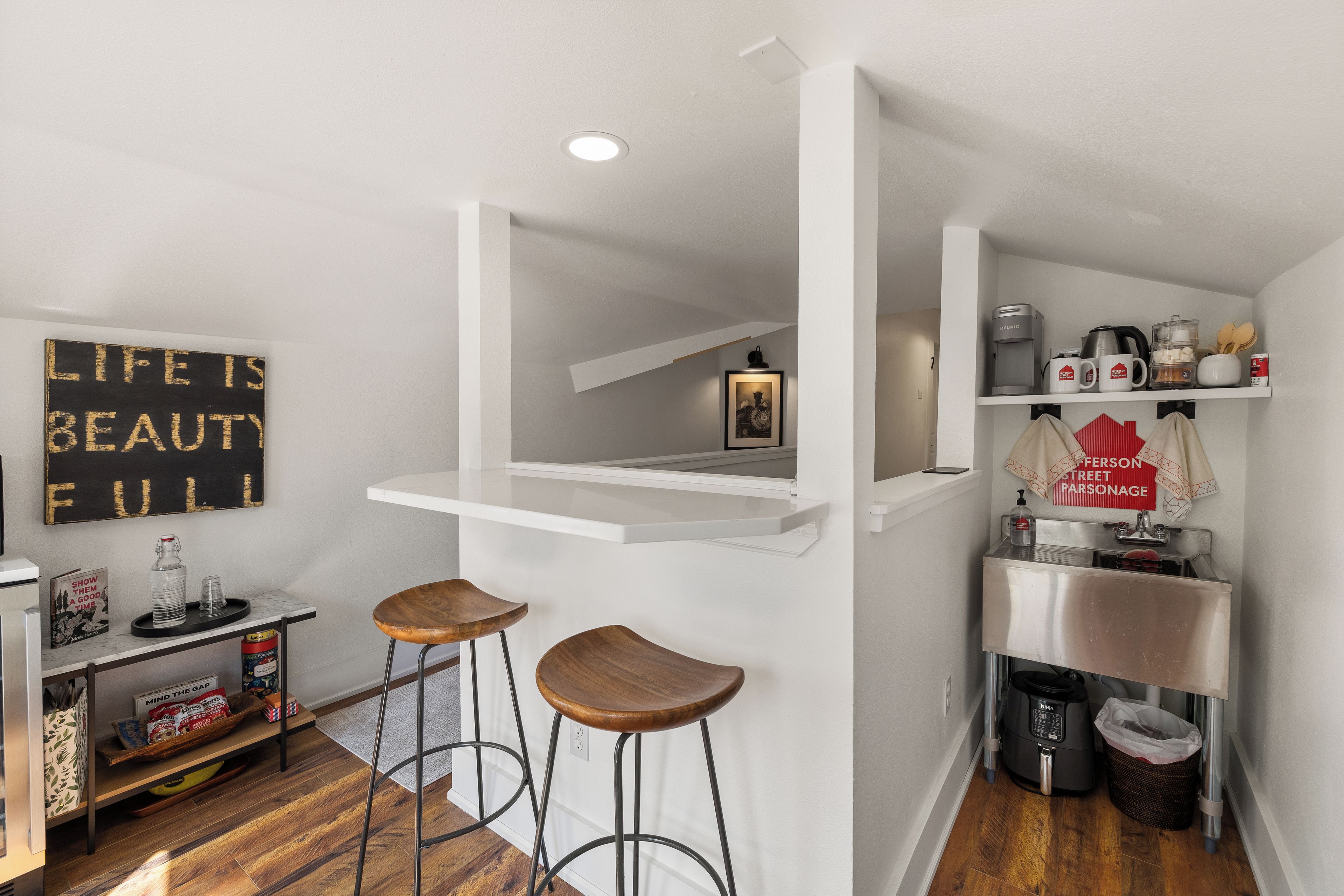 A modern kitchen with a bar area, a coffee machine, and a sign that reads 'LIFE IS BEAUTIFUL.'
