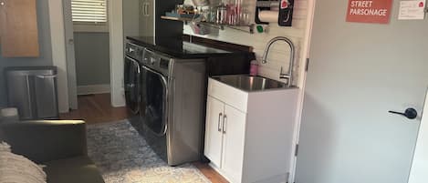 Una cucina compatta con lavatrice integrata, un lavello e un piccolo piano di lavoro.