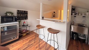 Una cocina compacta con microondas, refrigerador y una barra con taburetes.