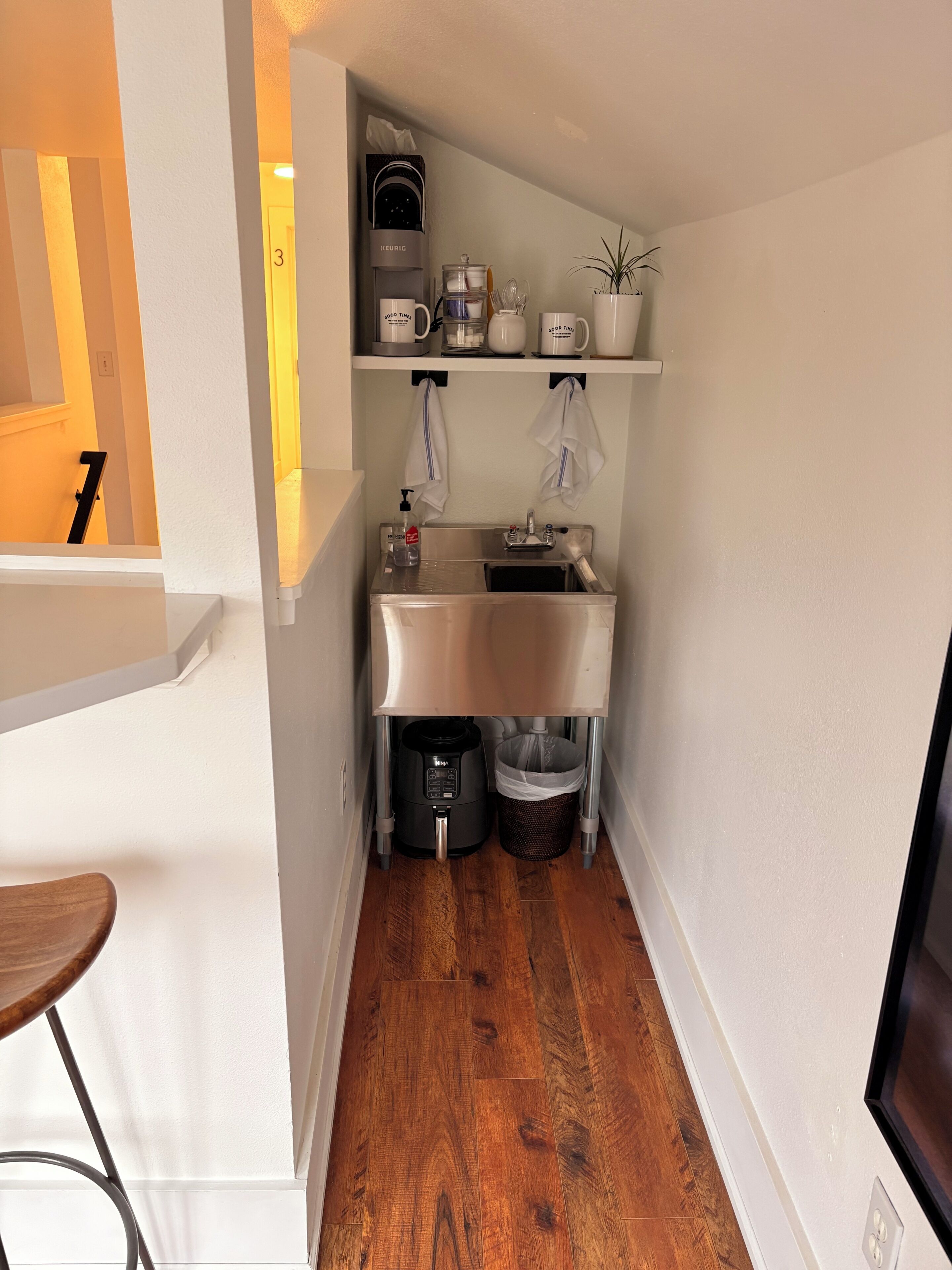 A compact kitchen with a coffee maker, kettle, and a small sink.