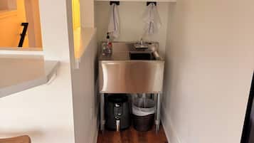A compact kitchen with a coffee maker, kettle, and a small sink.