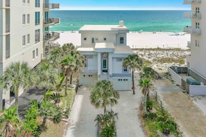 A multi-story building with balconies overlooking a beach and ocean.