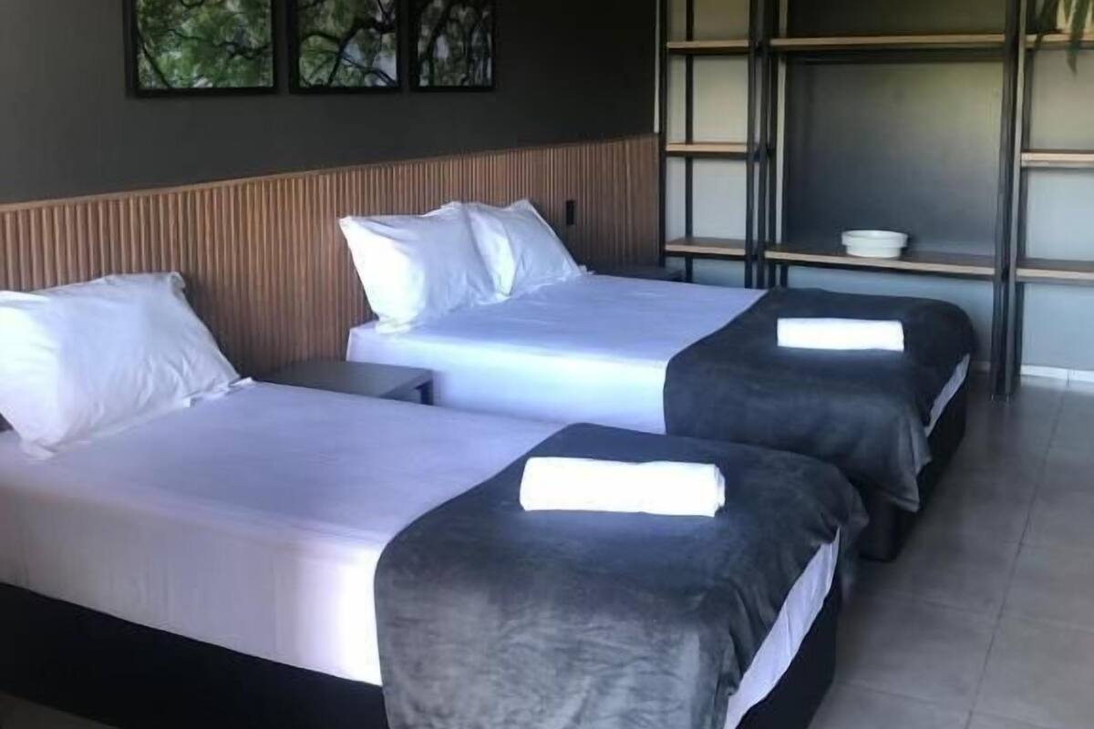 A hotel room with two beds, a ceiling fan, and artwork on the wall.