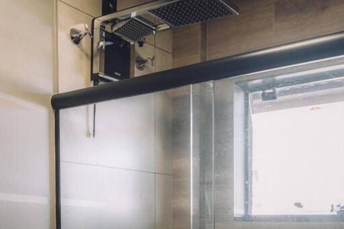 A modern bathroom with a glass shower enclosure, a visible window, and a toilet.