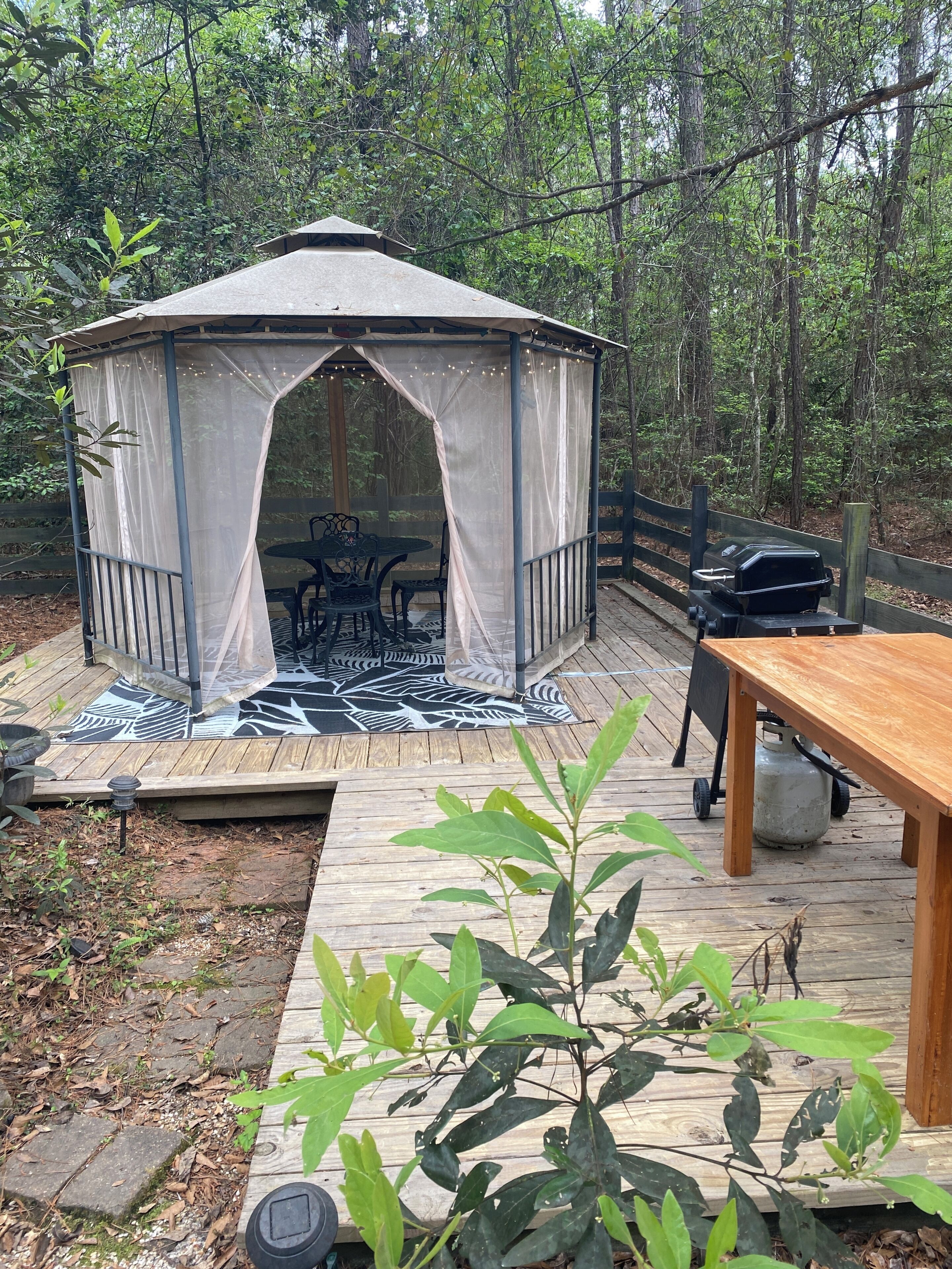 Une terrasse en bois avec un belvédère, des sièges d’extérieur et un barbecue.