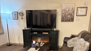 Ein Wohnzimmer mit Kamin, Fernseher, Sofa und Couchtisch.
