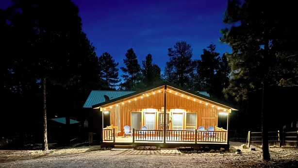 A wooden cabin with a porch, a dining area, and a large window. - Greer Mountain Cabin: Scenic Deck, Rustic Charm & Stress-Free Parking (Greer)