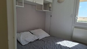 Ein Schlafzimmer mit Bett, Fenster und Einbauschränken.