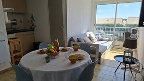 Ein Essbereich mit Tisch für zwei Personen, eine Küche im Hintergrund und ein Balkon mit Aussicht.