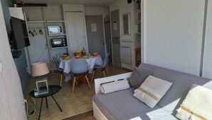 Ein kompakter Wohnraum mit Küchenzeile, Essbereich und einer Couch.