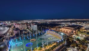 A nighttime aerial view of a cityscape with a large, illuminated plaza with circular patterns, surrounded by buildings and a body of water. - Luxury 1BR w/ Amazing views & Full Kitchen (Las Vegas)