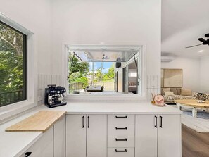 A modern kitchen with a built-in espresso machine, a large window, and a view of the outdoors.