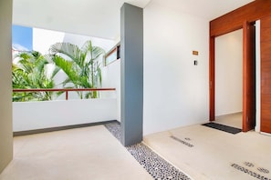 A modern interior with a balcony, a wooden door, and a tiled floor. - Cozy 1BR Condo in TAO Akumal w/ Terrace (Akumal)