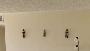 Een woonkamer met een bank, een stoel, een lamp en decoratieve objecten aan de muur.