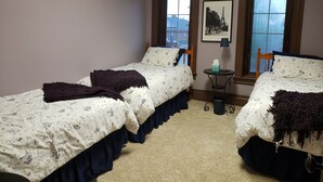 A bedroom with two single beds, a small table with a lamp, and a framed picture on the wall.