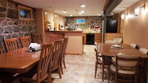 A spacious kitchen with a stone wall, wooden dining table, and chairs.