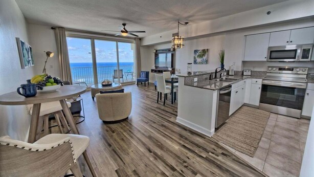 A modern kitchen with a central island, a dining area with a view, and a balcony with a view.