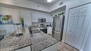 A modern kitchen with granite countertops, stainless steel appliances, and white cabinetry.