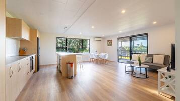 A modern kitchen with a dining area, a sofa, and a TV.