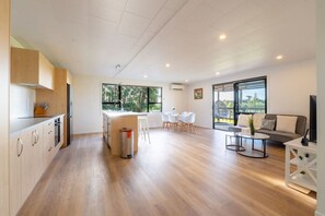 A modern kitchen with a dining area, a sofa, and a TV.