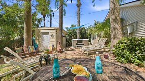 Un patio con mobili da esterno, un tavolo con bevande e un piccolo edificio sullo sfondo.