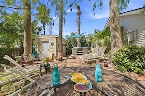 Eine Terrasse mit Gartenmöbeln, einem Tisch mit Getränken und einem kleinen Gebäude im Hintergrund.