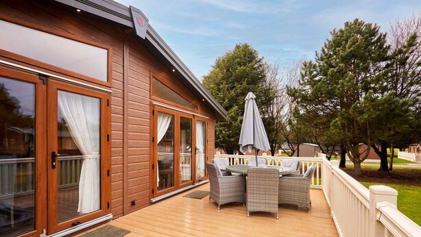 Eine Holzterrasse mit Whirlpool, Korbmöbeln und einem überdachten Patio.