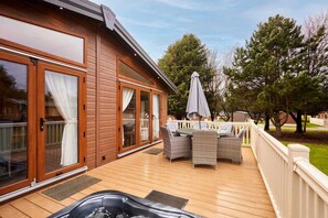 A wooden deck with a hot tub, wicker furniture, and a covered patio area. - Host Stay Bramble Lodge (York)
